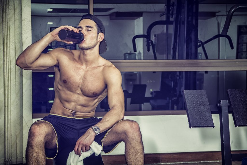 man at gym drinking post-workout recovery beverage
