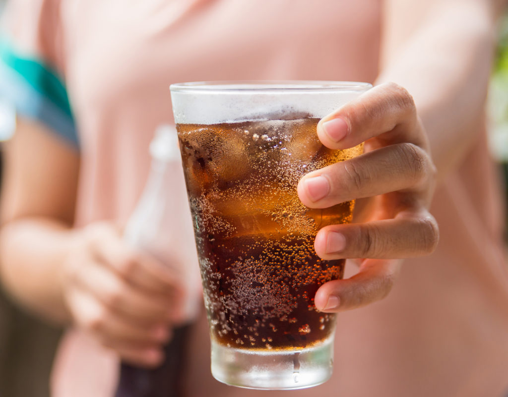 Woman hand giving glass of cola.Glass of cola Soft drinks with ice.