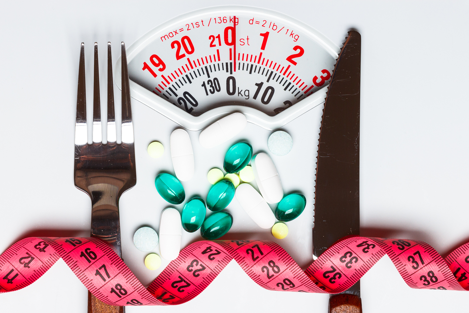 Healthy eating medicine health care food supplements and weight loss concept. Pills with measuring tape on white scales